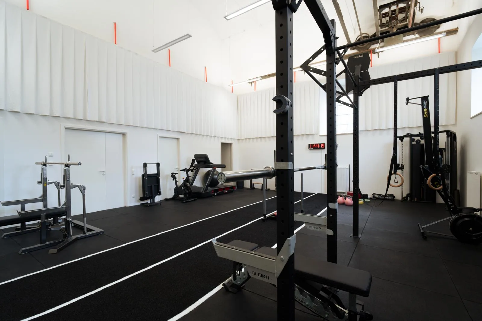 Trainingshalle mit Laufbahn und Krafttrainingsgeräten aus seitlicher Perspektive