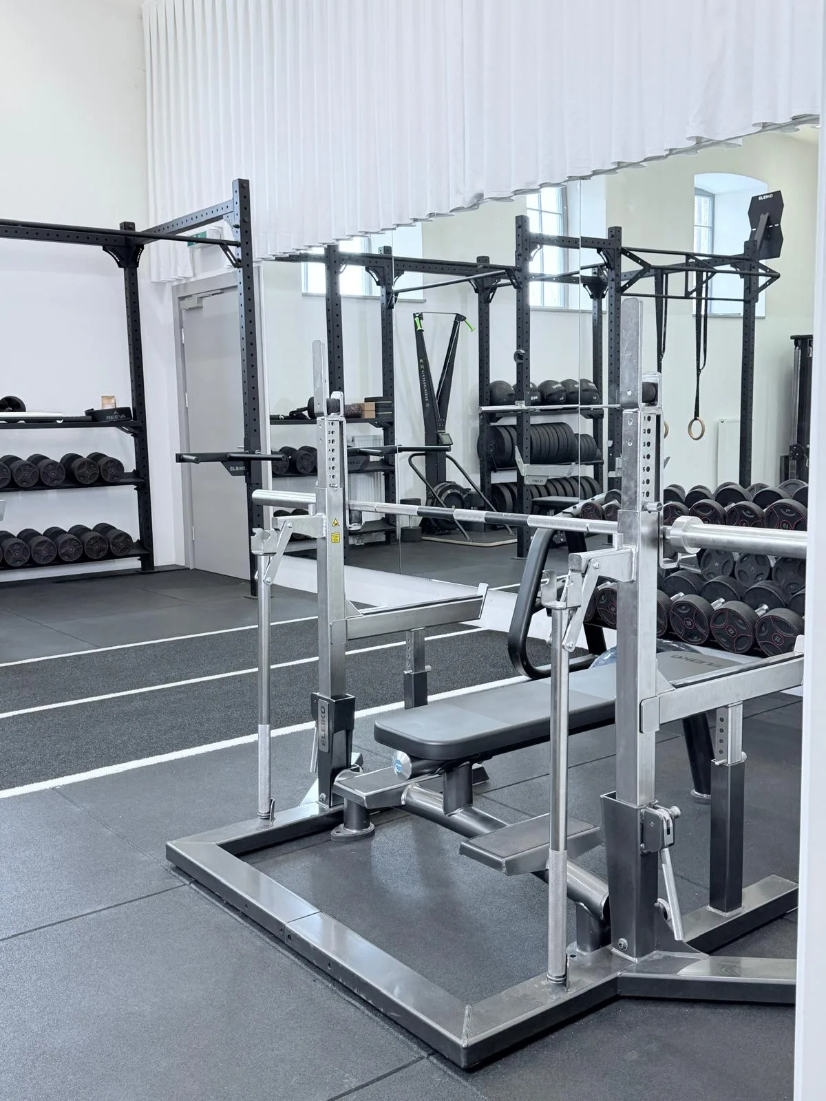 Trainingsfläche mit Langhantelstation, Hanteln und Spiegelwand