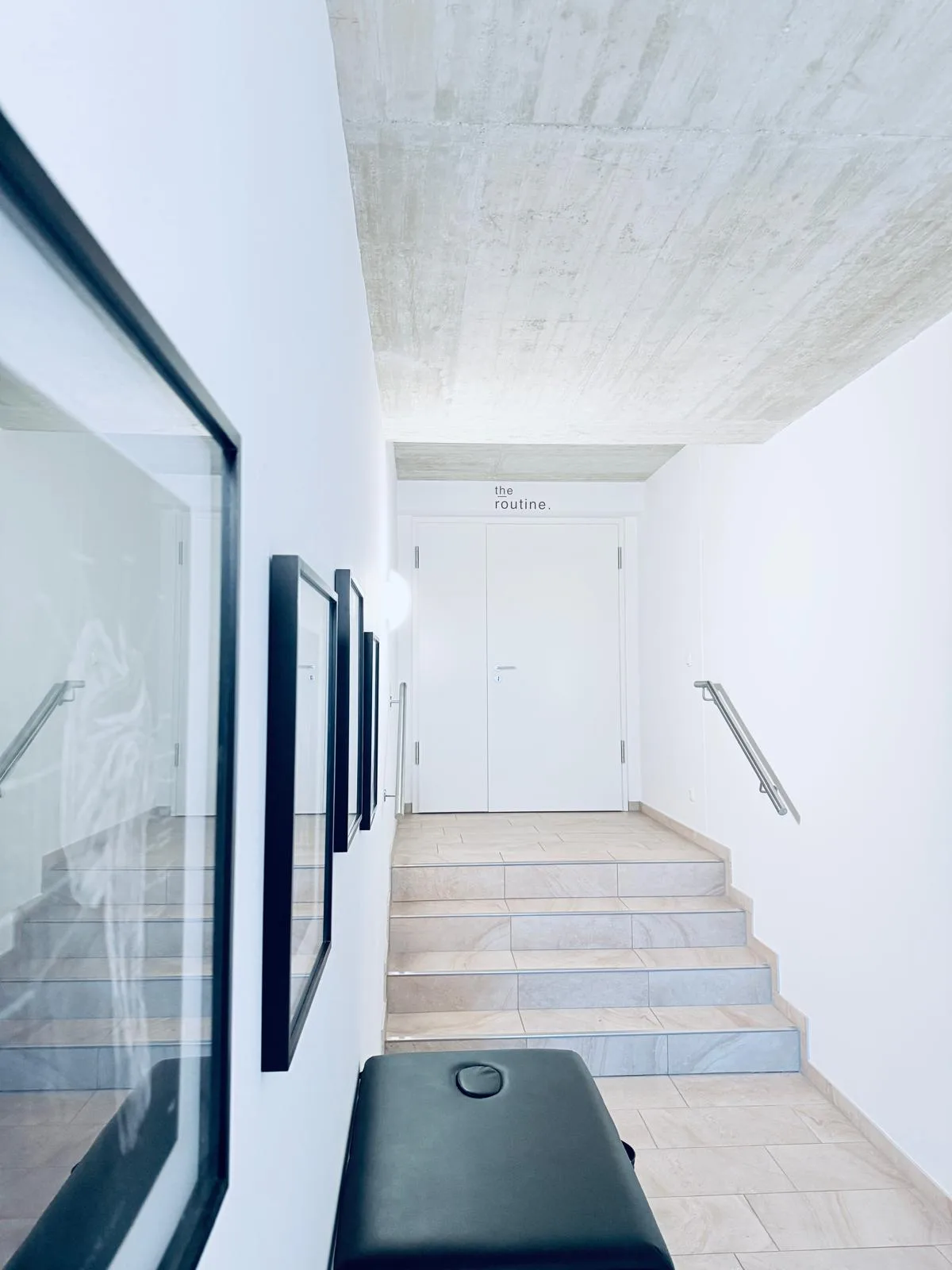 Heller Flur im Training House mit Behandlungsliege und Treppe